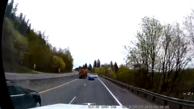 WATCH: Driver caught on camera between log truck and another car